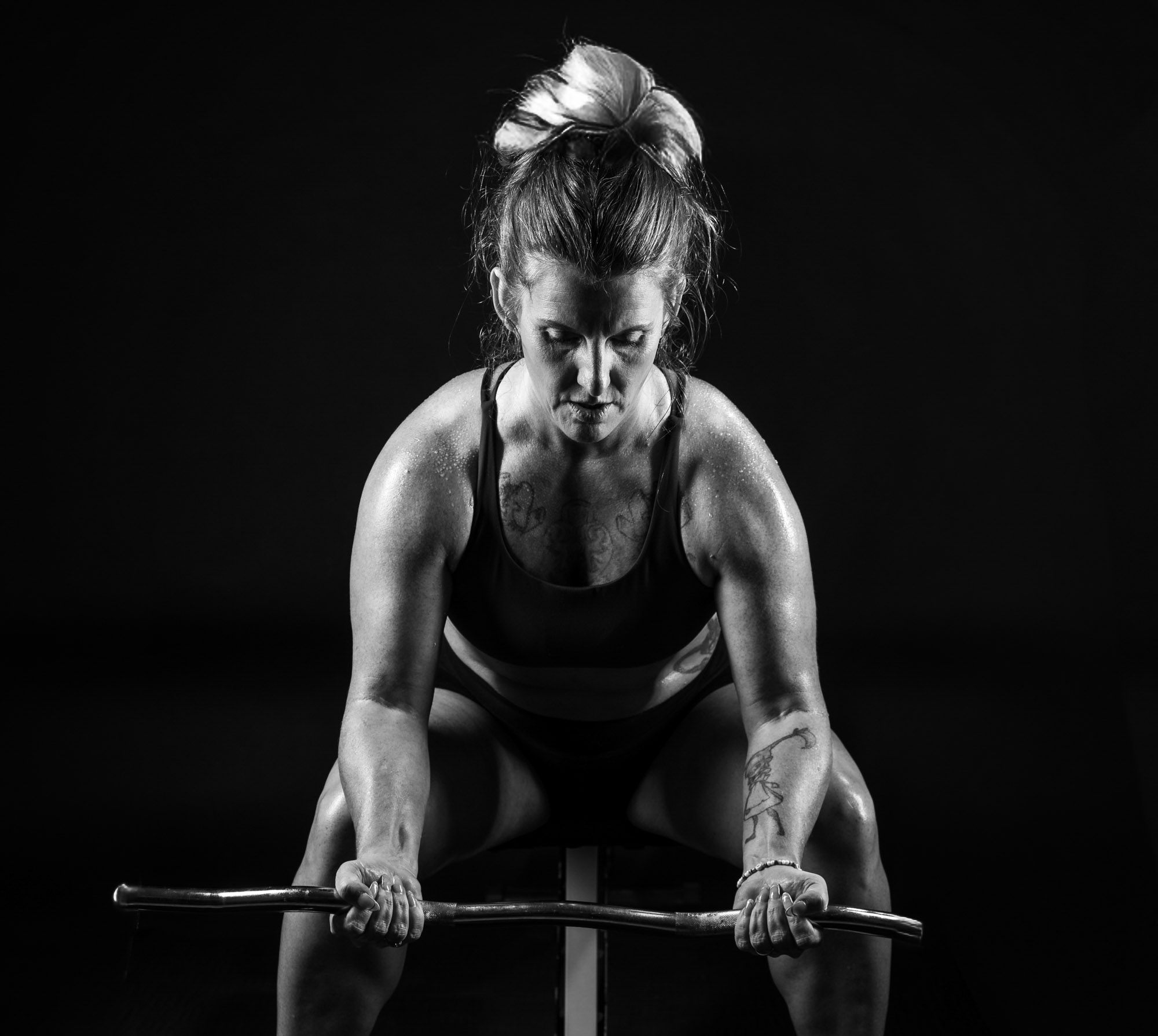 Billie Jo, personal trainer at 4Letter Lifts, preparing to lift a barbell
